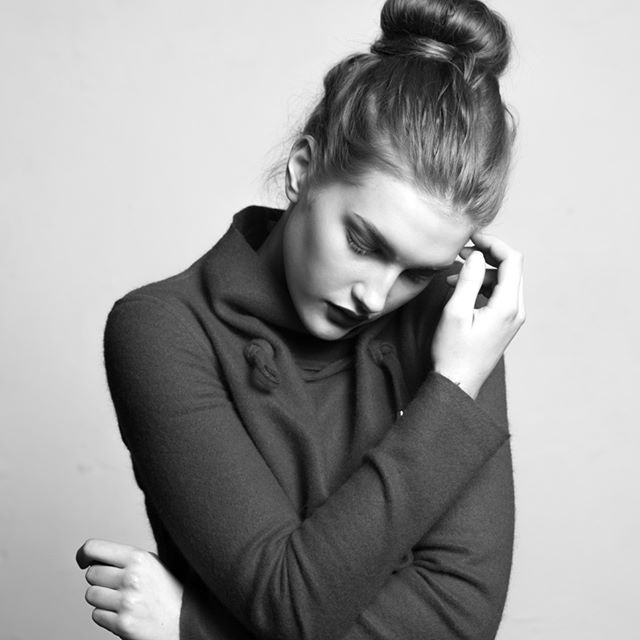 A monochrome portrait of a young woman with a bun hairstyle in a thoughtful pose.