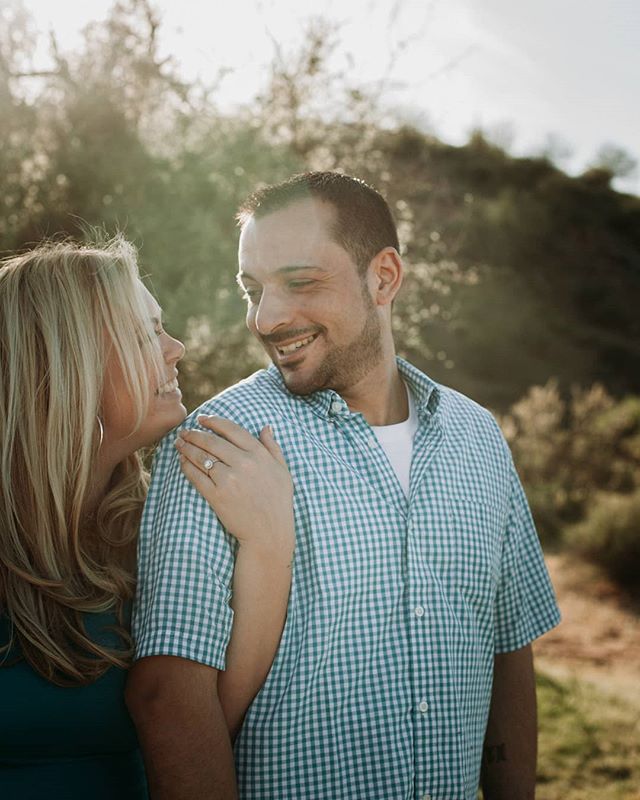 A happy couple shares an intimate moment together in a sunlit outdoor setting.