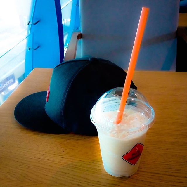 A drink with a straw and a hat on a table, creating a casual still life.