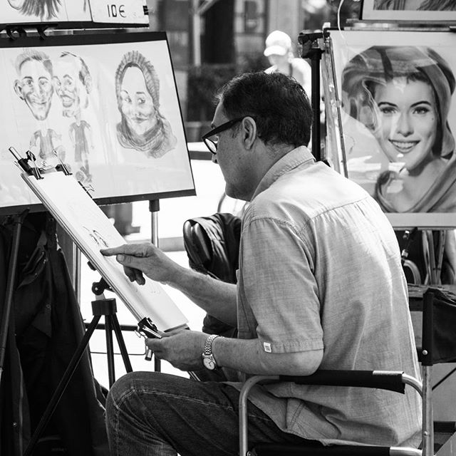 An artist drawing portraits at an outdoor art fair.
