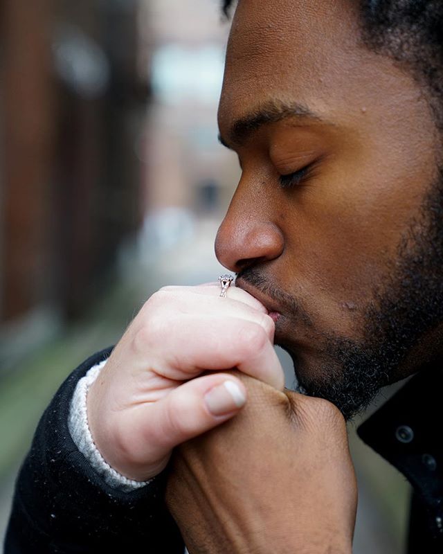 A man kisses a hand wearing an engagement ring in a tender moment, showcasing love and commitment.