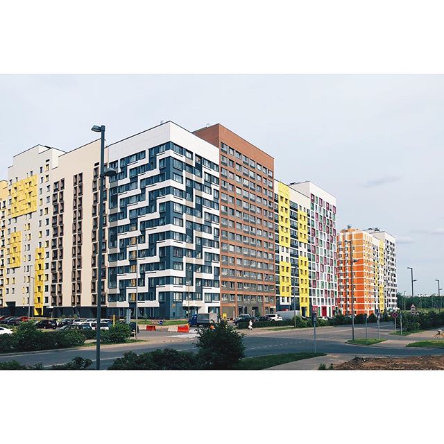 A view of modern colorful residential buildings along a city street on a clear day. A vibrant urban scene.