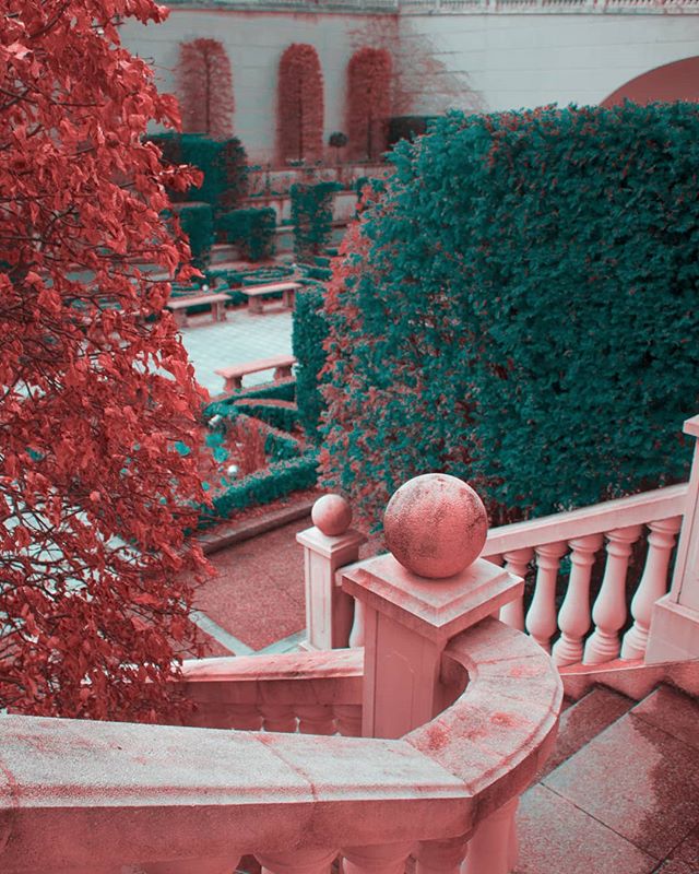 A tranquil garden vista showcases perfectly manicured hedges, a classic stone staircase, and artistic sculptural elements.