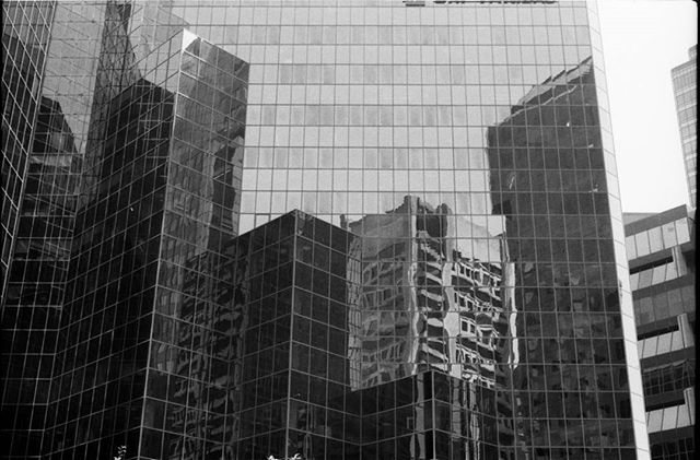 A striking black and white photo of city skyscrapers with geometric lines and glass reflections, capturing modern urban architecture.
