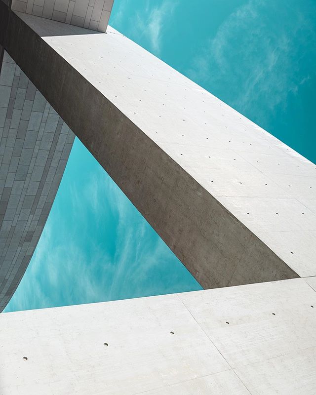 A low angle shot of modern concrete architecture against a teal sky creates a serene, minimalist urban scene.