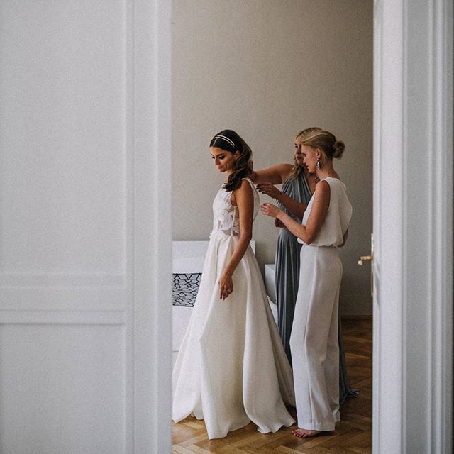 A bride gets ready for her wedding with the help of her bridesmaids in a soft, natural light setting.