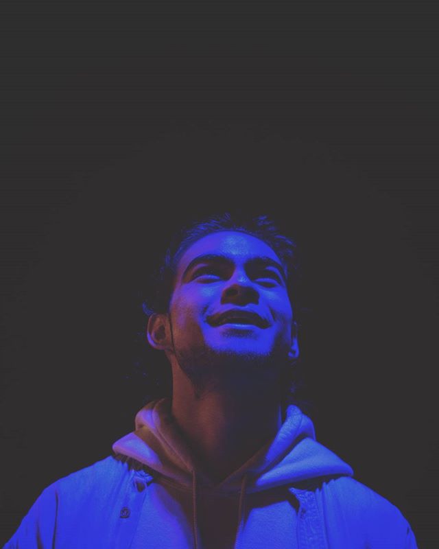 A man looking up with blue and purple lighting creating a hopeful and optimistic atmosphere.