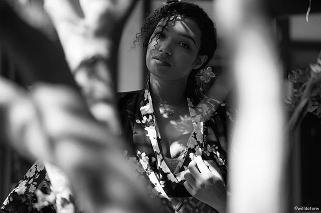Monochrome portrait of a woman with curly hair, framed by branches, creating a dreamy, elegant vibe.