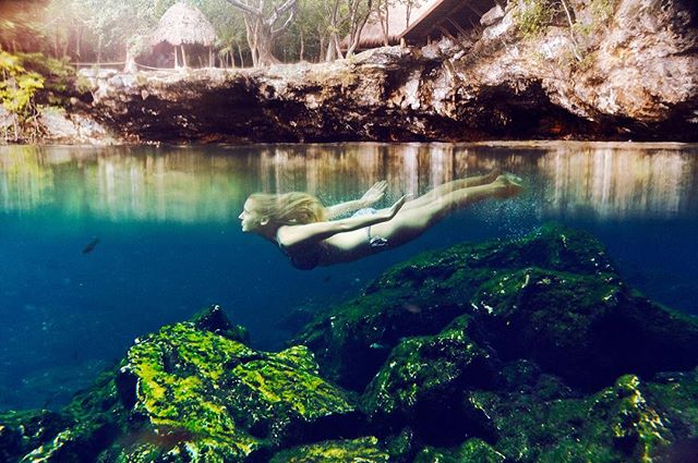 A woman swims in a tranquil, clear cenote, showcasing the beauty of nature and a peaceful lifestyle.