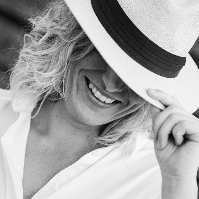A smiling person wearing a hat. Black and white image, great for well-being content.