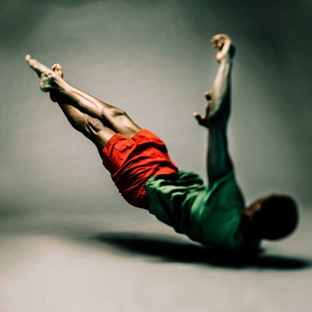 Athletic man performs an intense dance move in a studio setting, showcasing strength and flexibility.