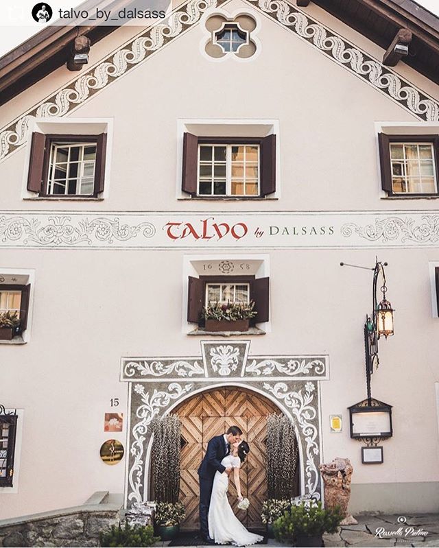 A newlywed couple share a kiss in front of an ornate building, perfect for wedding or romantic getaway marketing.