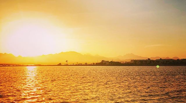 A sunset over the water creates a serene view, perfect for travel and relaxation themes.