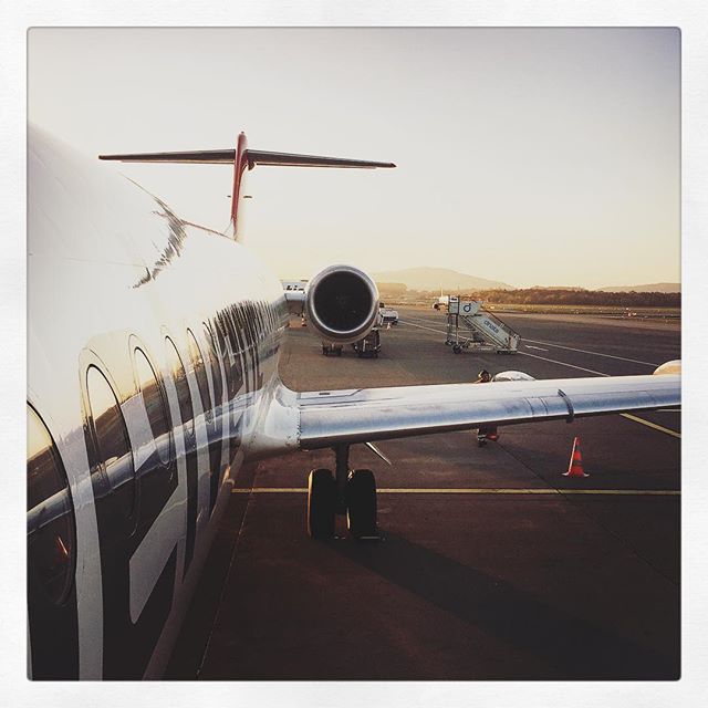An airplane is parked on the tarmac at sunset, ready for takeoff or arrival at its destination.
