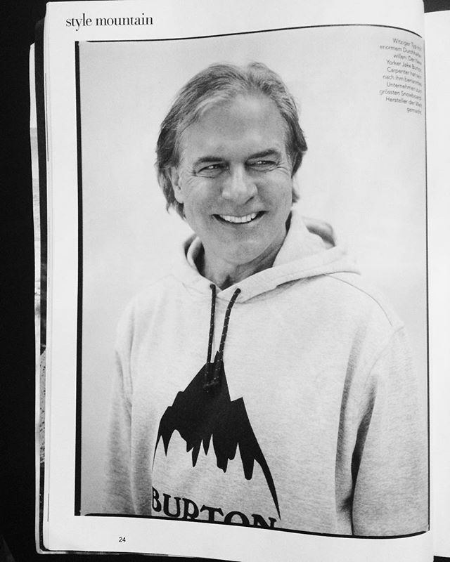 Monochrome portrait of a smiling man wearing a Burton hoodie, likely for an editorial or advertisement.