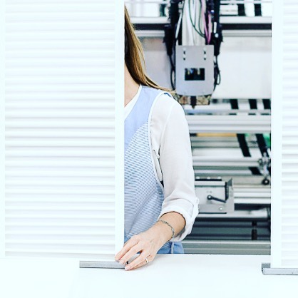 Woman working with precision machinery in a bright, modern workshop setting. Quality control.