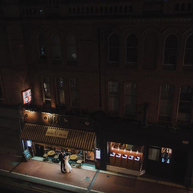 A couple embraces outside a restaurant at night, bathed in the warm glow of the city.