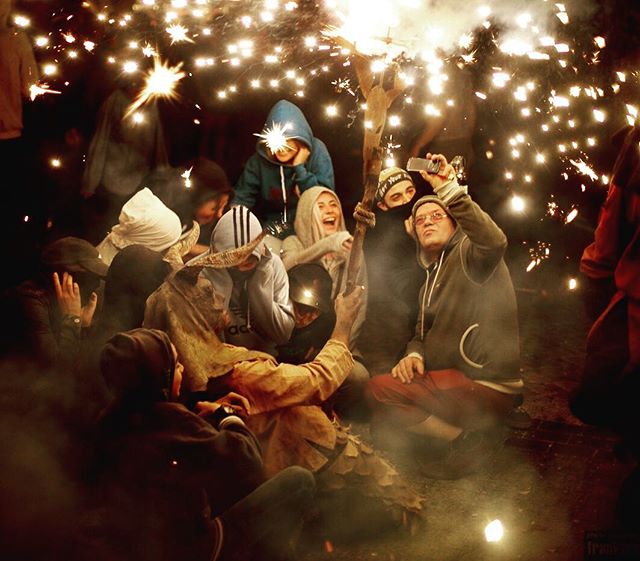 A group of people celebrating with sparklers at night during an outdoor event.