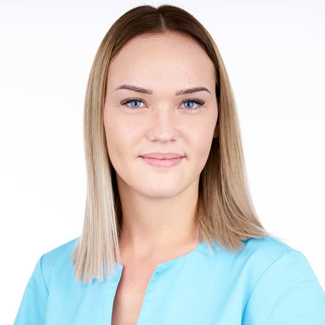 Professional headshot of a young woman with blonde hair in a blue top against a white background.