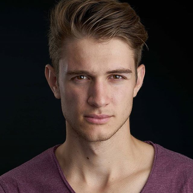 Professional headshot of a confident young man against a dark background, ideal for corporate branding and social media.