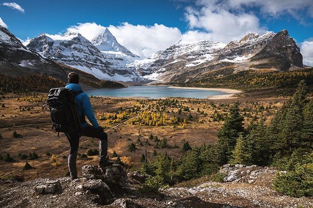 A man with a backpack gazes at a mountain lake, capturing the essence of outdoor adventure and a calm, serene landscape.