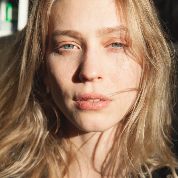 Close-up portrait of a blonde woman with blue eyes in soft light, perfect for beauty and skincare campaigns.