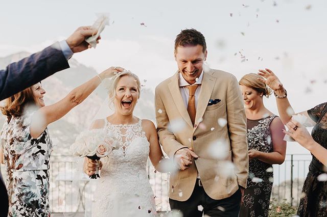 A newly married couple is showered with confetti while surrounded by happy guests at their wedding reception.