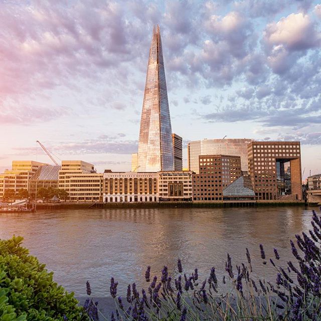 London skyline featuring The Shard skyscraper along the River Thames at sunset, showcasing iconic architecture.