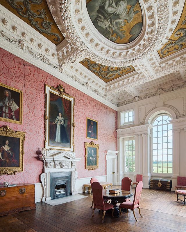 An ornate room with paintings, furniture, and a fireplace exudes classic elegance.
