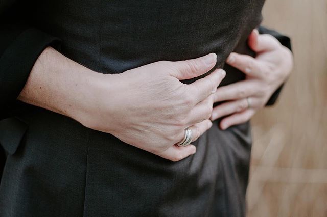 A close-up shows a person being embraced, hands clasped, wearing a wedding ring.