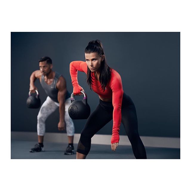 A woman and a man are working out with kettlebells in a fitness studio.