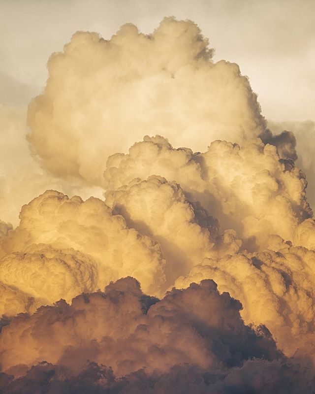 Fluffy, amber-colored clouds fill the sky, creating a dreamy, serene atmosphere.