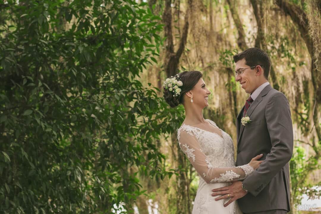 A newlywed couple shares a loving glance amidst a lush forest backdrop on their wedding day.