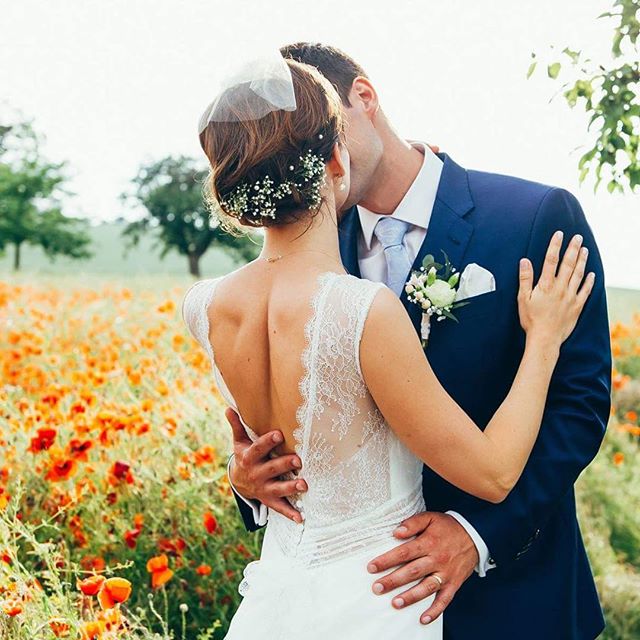 A bride and groom share a tender moment in a field of flowers on their wedding day.