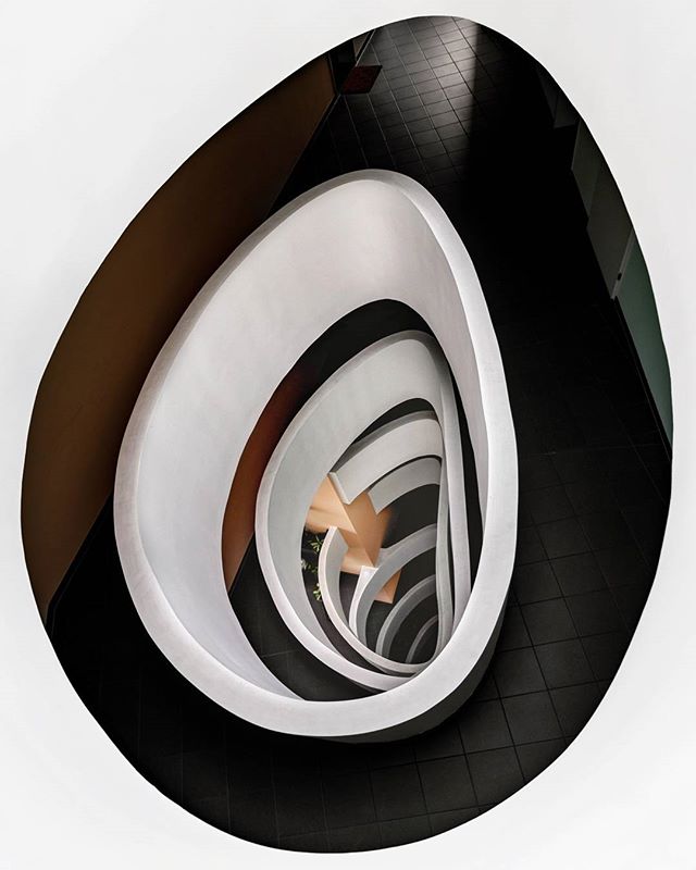 A captivating low-angle view of a spiraling staircase in a modern architectural building, showcasing artistic design and elegance.
