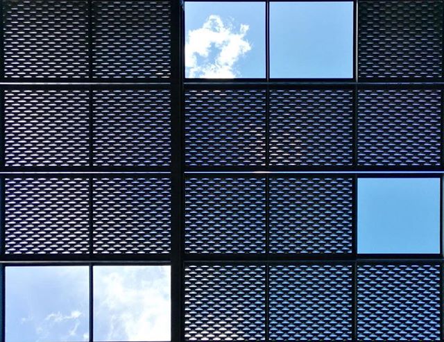 A modern building facade with a lattice pattern and blue sky visible through the windows creates a serene urban view.