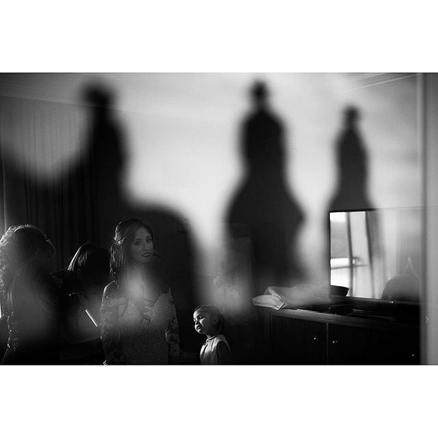 A black and white photograph captures a woman and child with shadows projected on a wall, creating an intimate and artistic scene.