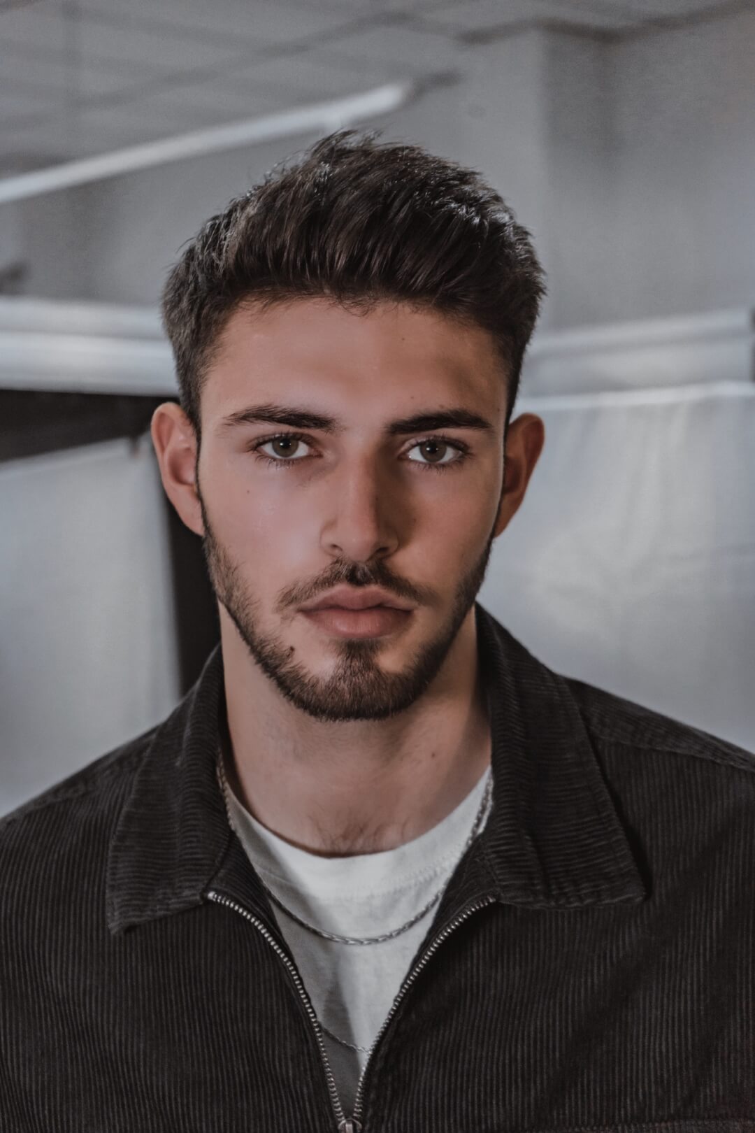 A handsome man with a beard poses for a portrait in soft, natural light.