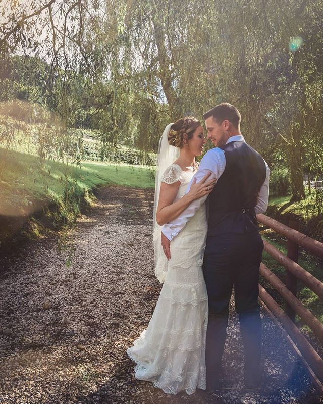 A bride and groom share an intimate moment on their wedding day on a natural path.