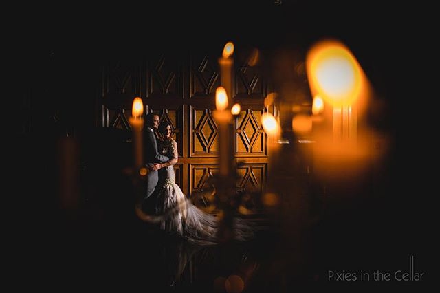A bride and groom embrace in a candlelit, romantic wedding venue, creating a dreamy and intimate moment.