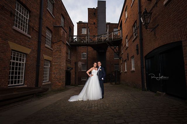 A bride and groom pose in a brick courtyard after their wedding ceremony.