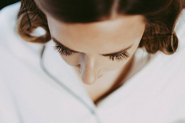 A close up of a woman's face shows soft makeup and skin in a bright, dreamy, editorial style.