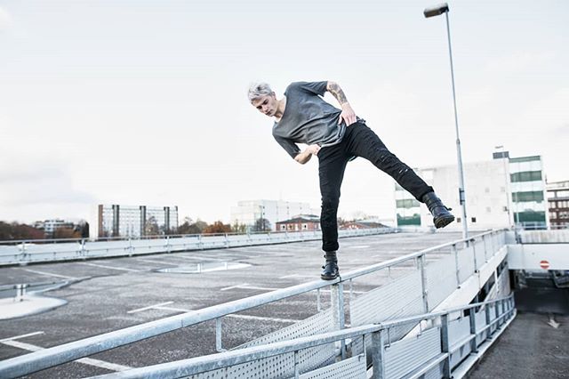 A man practices parkour on a rooftop in an urban setting.