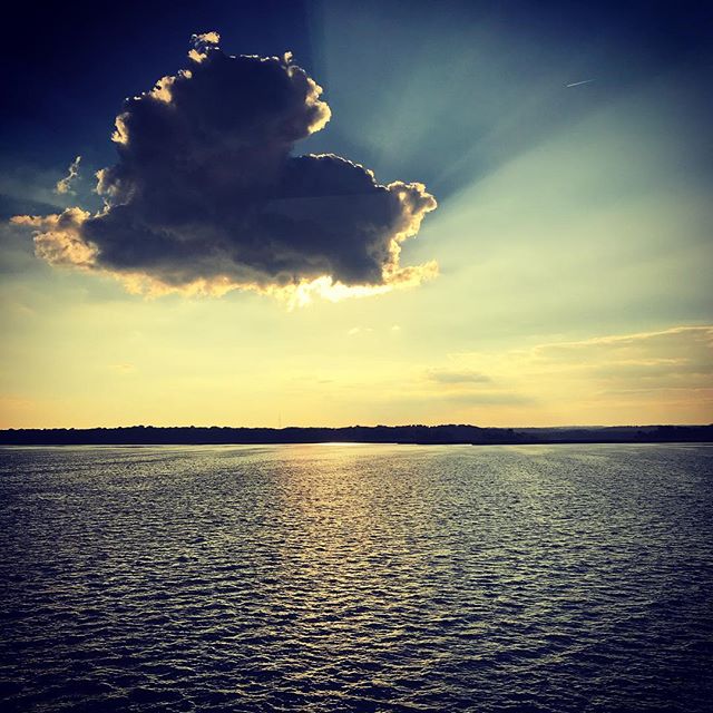 A scenic view of a serene lake reflecting the warm sunset and a dramatic cloud formation in the sky.