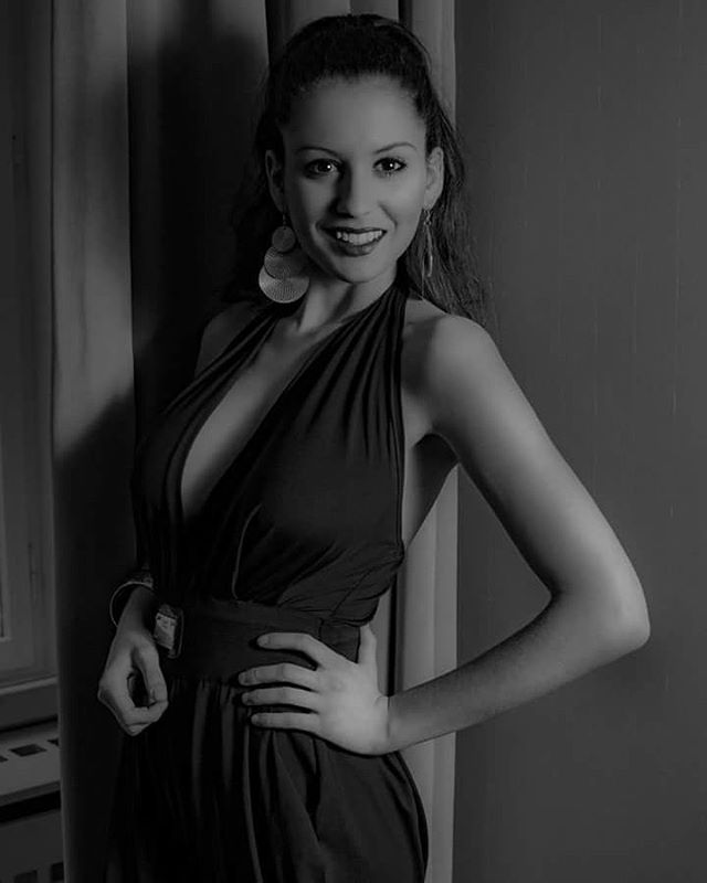 Elegant woman in a dress poses confidently for a studio portrait.