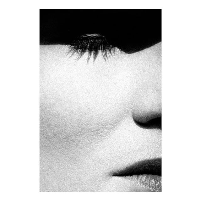 A close-up black and white image of a woman's face highlighting her soft skin, eye, nose, and lips.