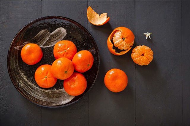 A vibrant image featuring a variety of fresh tangerines arranged on a dark surface, creating a visually appealing still life.
