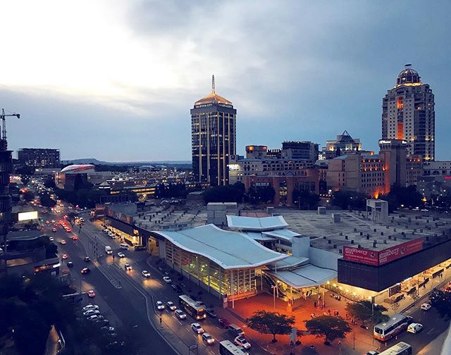 Cityscape view featuring buildings, traffic and illuminated skyscrapers at twilight.