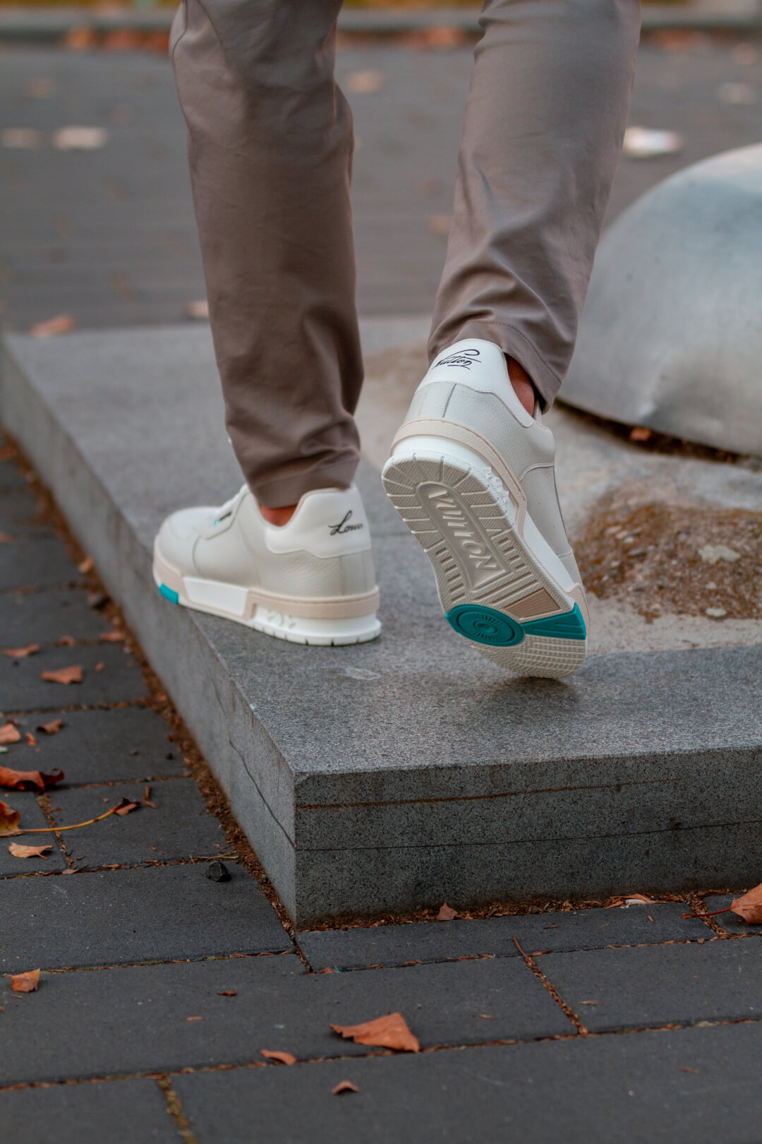 A person walks in designer sneakers on a city street, showcasing modern footwear and urban style.