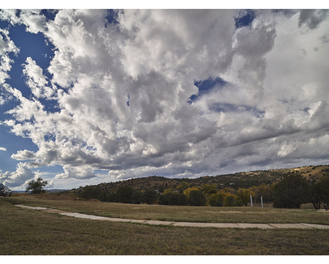 Fluffy white clouds with blue sky peeking through behind